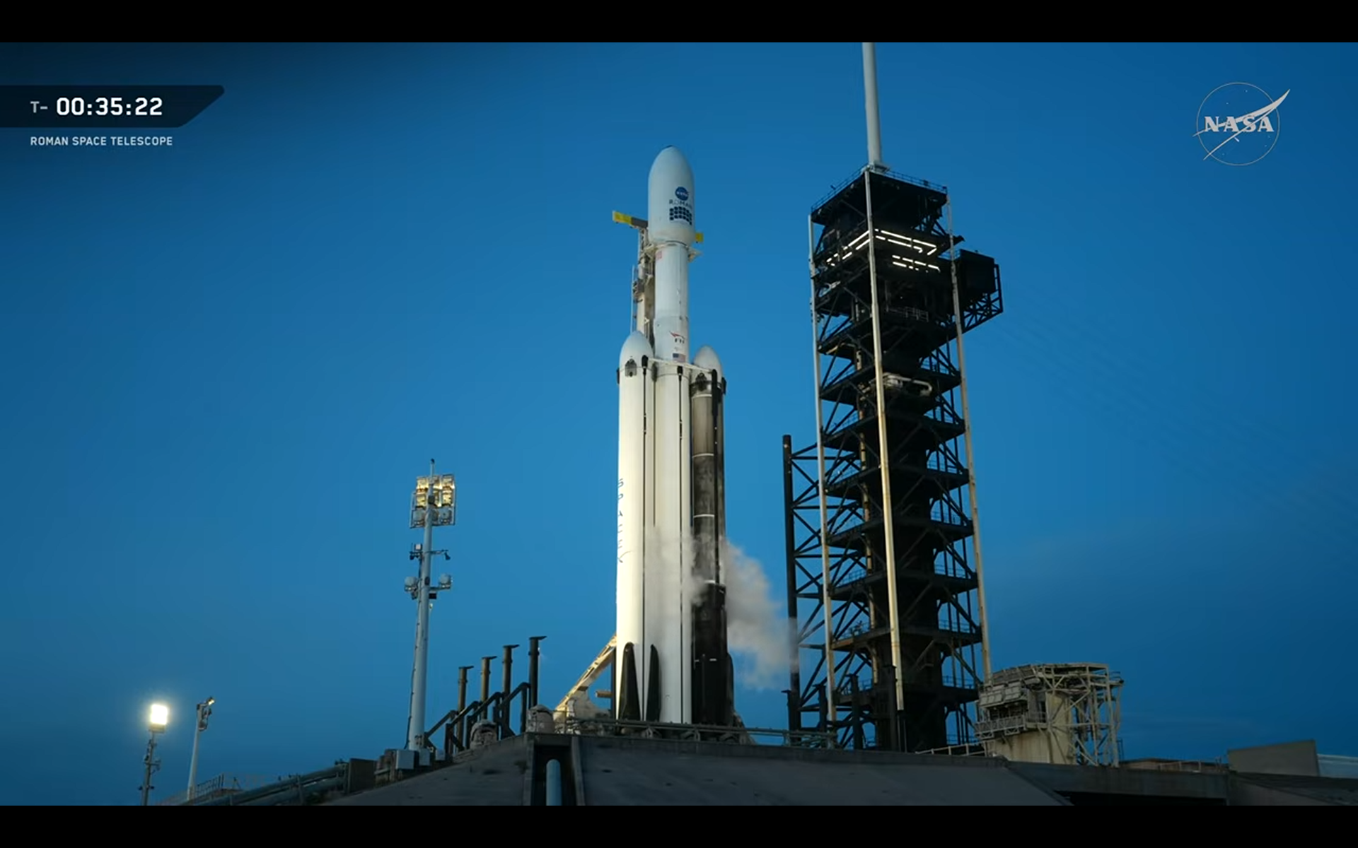 A SpaceX Falcon Heavy triple core rocket on the pad being fueled for launch.