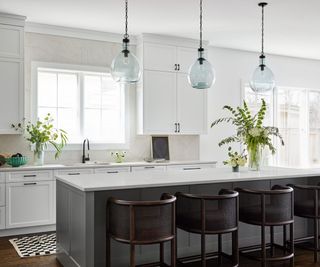 A white and dark green kitchen with marble countertops and backsplash