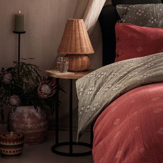 A Bohemian bedroom with patterned bedding and a straw table lamp