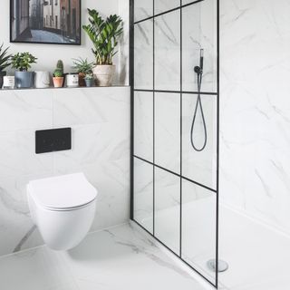 White marble bathroom with floating toilet and black crittal shower screen