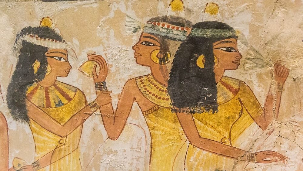 A painting of ancient Egyptians wearing head cones