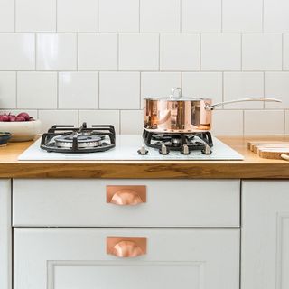 kitchen area with wooden worktop and stove and oven and copper container