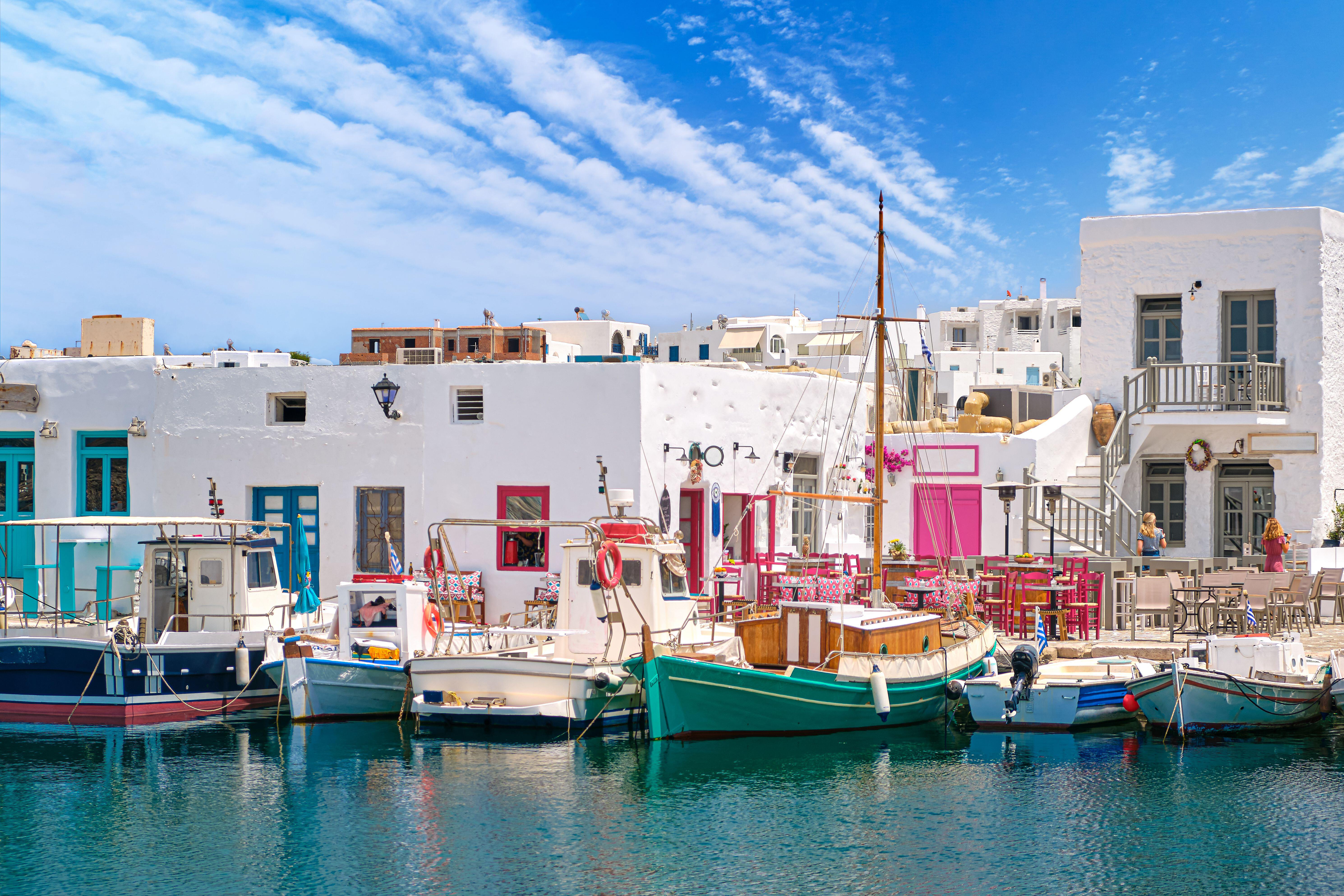 Brightly coloured fishing boats bob in a harbour directly infront of low, white, square houses