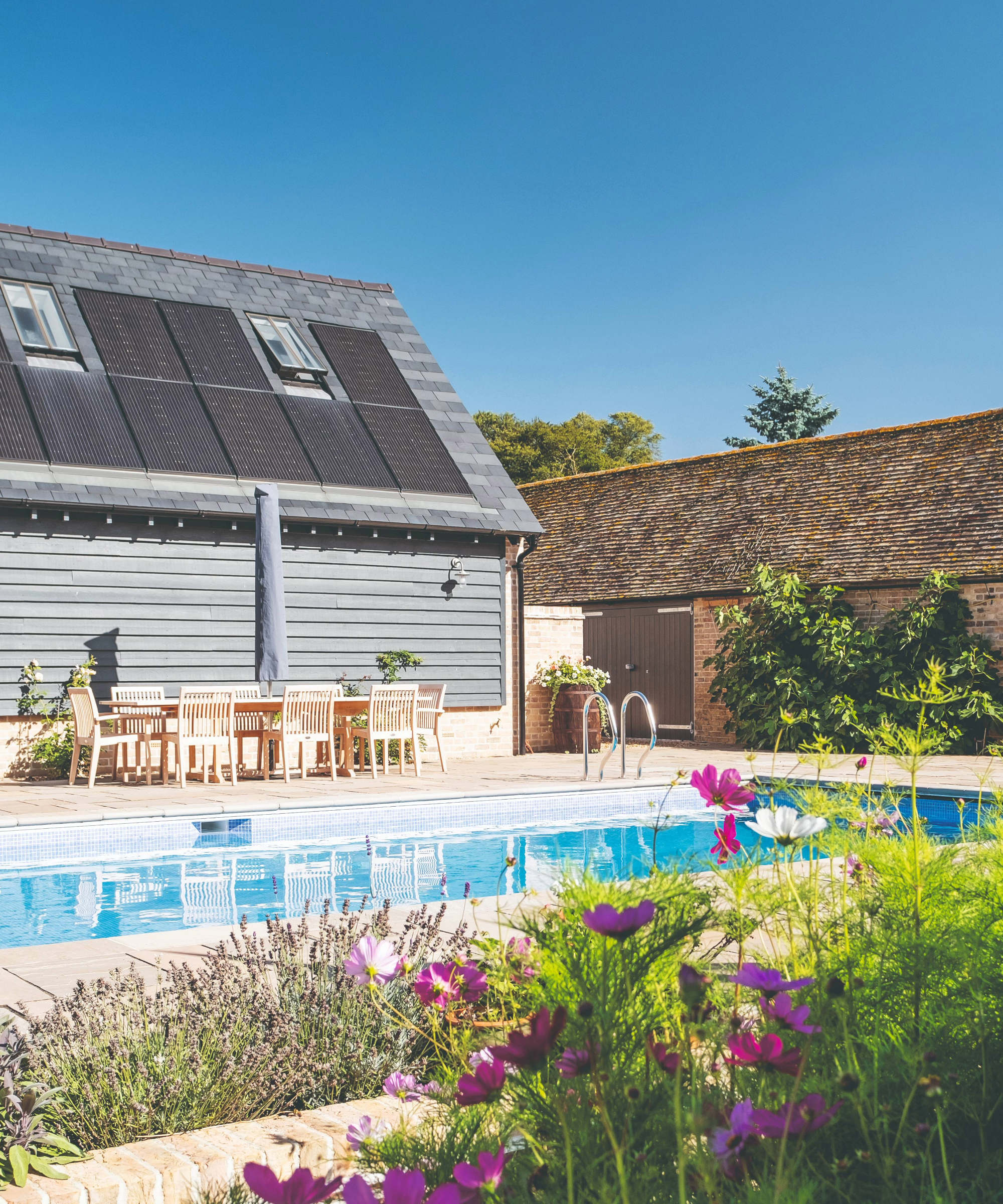 Outdoor pool next to flower beds and outdoor table