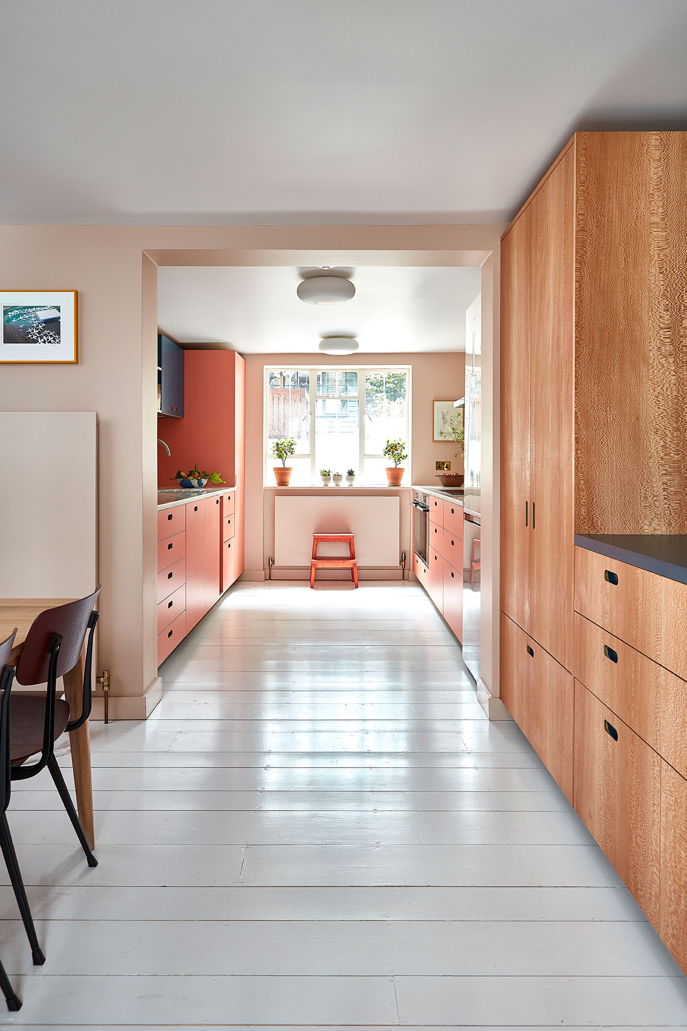 A look through from a dining ares into a streamlined galley kitchen in peach and wood