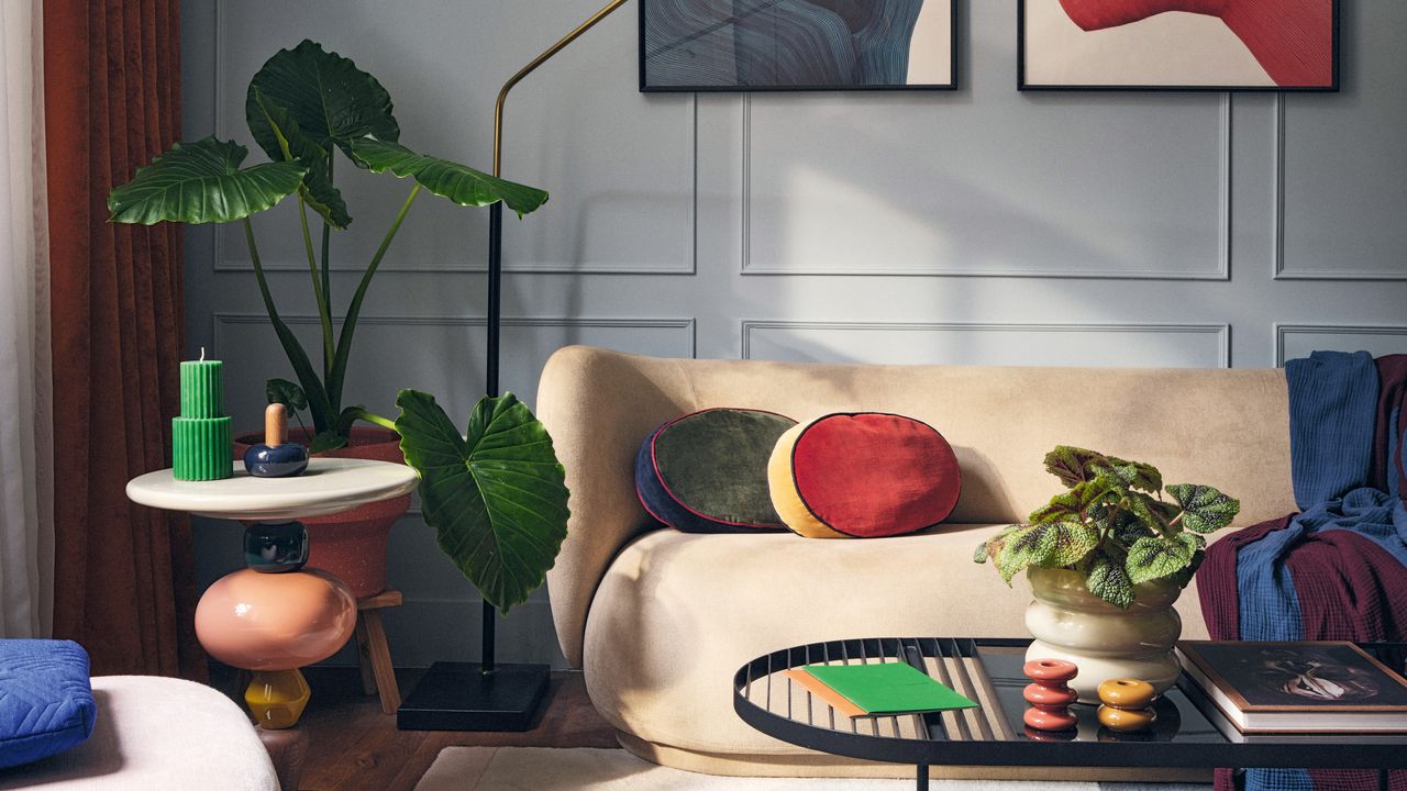 Living room with pale grey walls, pale yellow sofa, and punches of red, dark blue and bright green