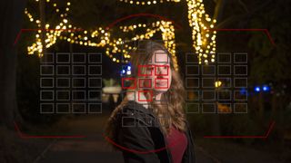 A woman smiling with fairy lights behind