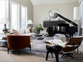 White living room with grand piano and mic-century chair with plush sofa