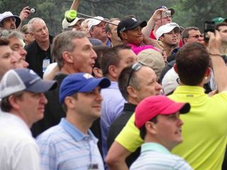 A face in the crowd: Tiger Woods drives off the 8th tee on Tuesday morning