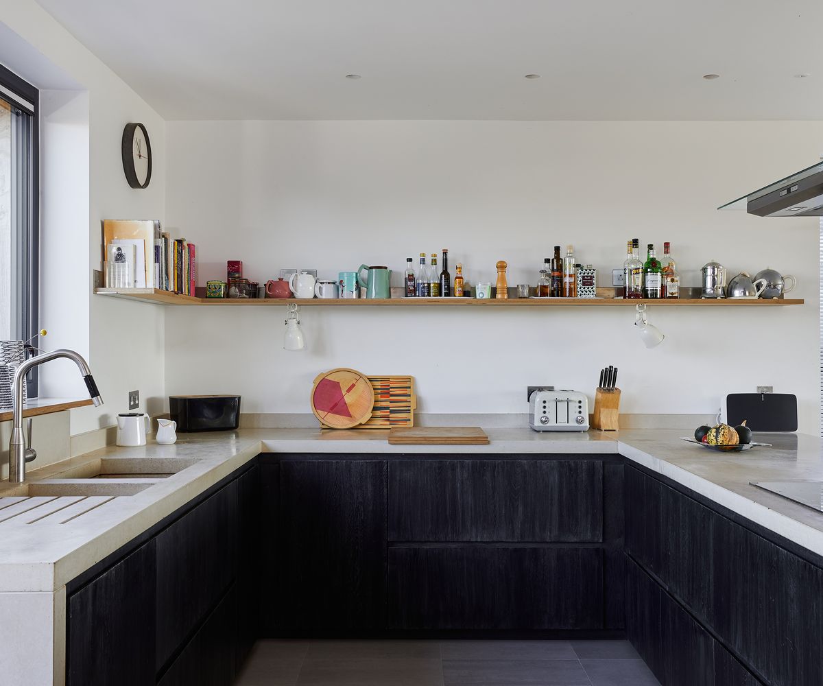 A U-shaped kitchen with white countertops and dark black timber drawers units