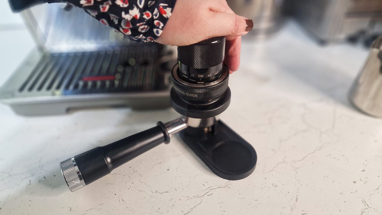 Person pressing ground coffee to use in the De'Longhi La Specialista Touch