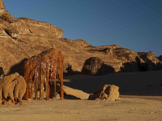 Desert X AlUla 2024 installation in the landscape, appearing like dripping resin over rocks