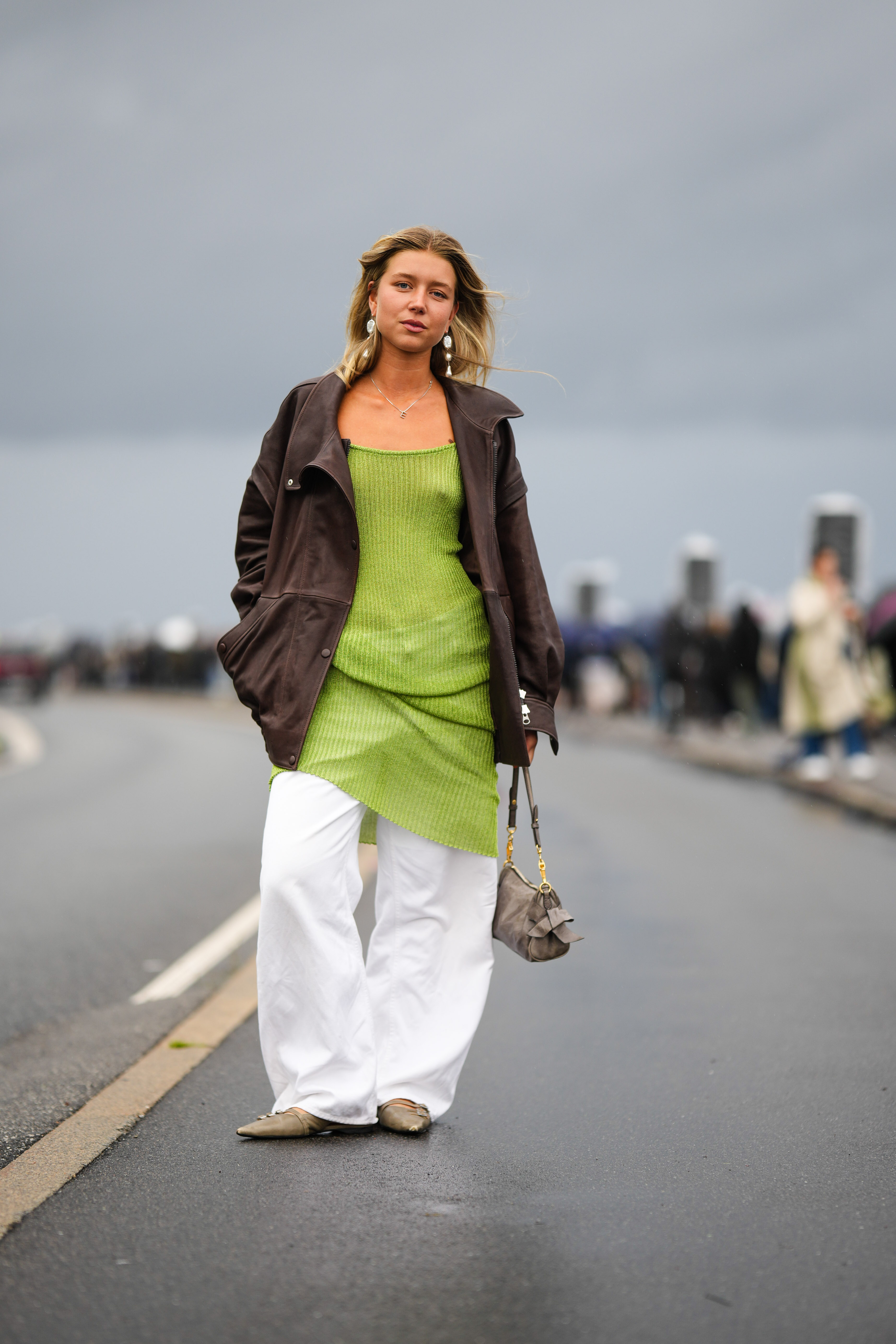 woman wearing green dress, brown jacket, and white pants