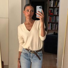 Influencer wearing a cream V-neck sweater and jeans