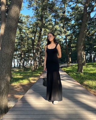 Woman in black maxi dress with sheer detail.