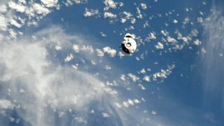 a white space capsule is seen against the blue earth