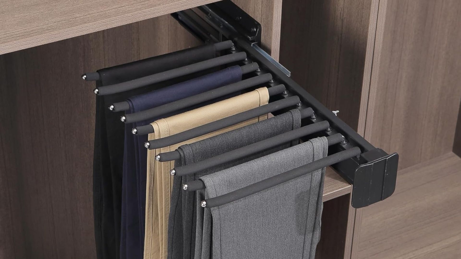 A black pull-out pants rack in a wooden wardrobe