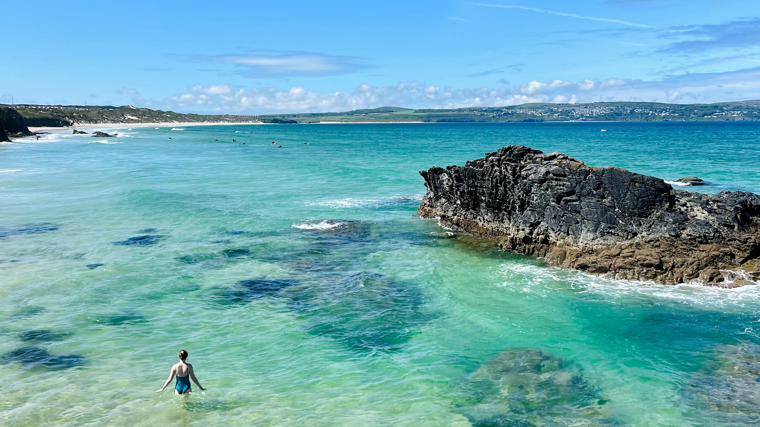 Woman in blue swimsuit swimming off the coast of Cornwall