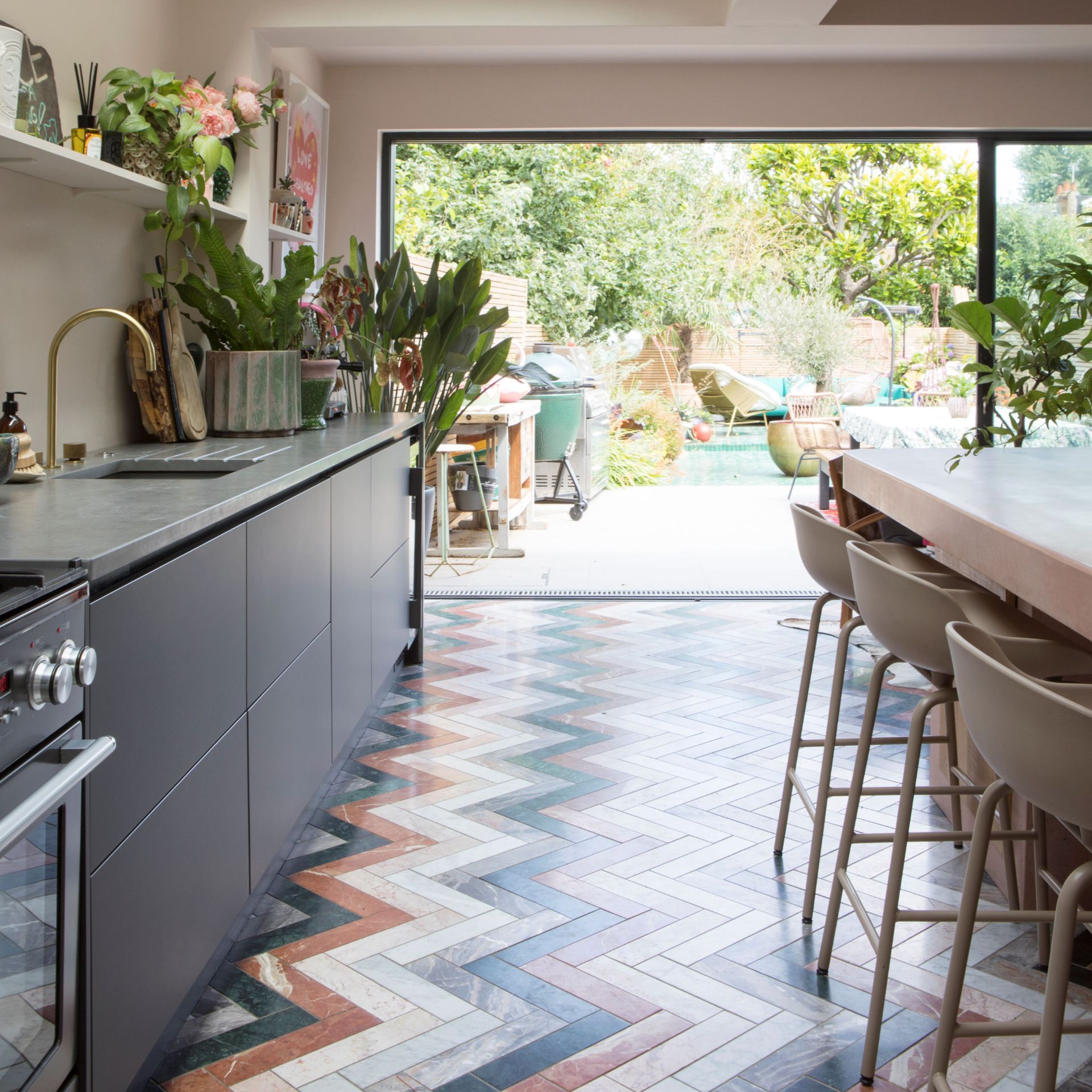 Open plan kitchen layout, handleless units, open shelving, kitchen island leading to bi-fold outdoor space