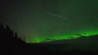 starlink satellites fly in front of green aurora