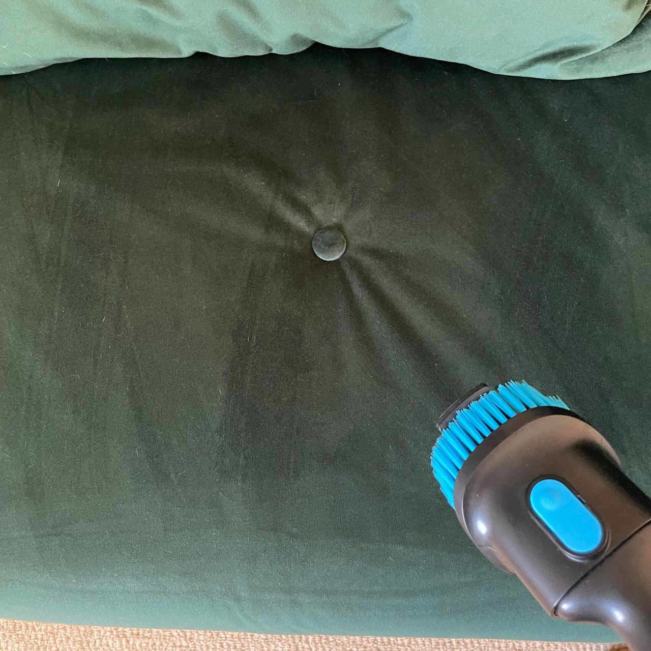 Using the upholstery tool on a green sofa bed