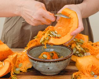 Woman scooping out pumpkin seeds