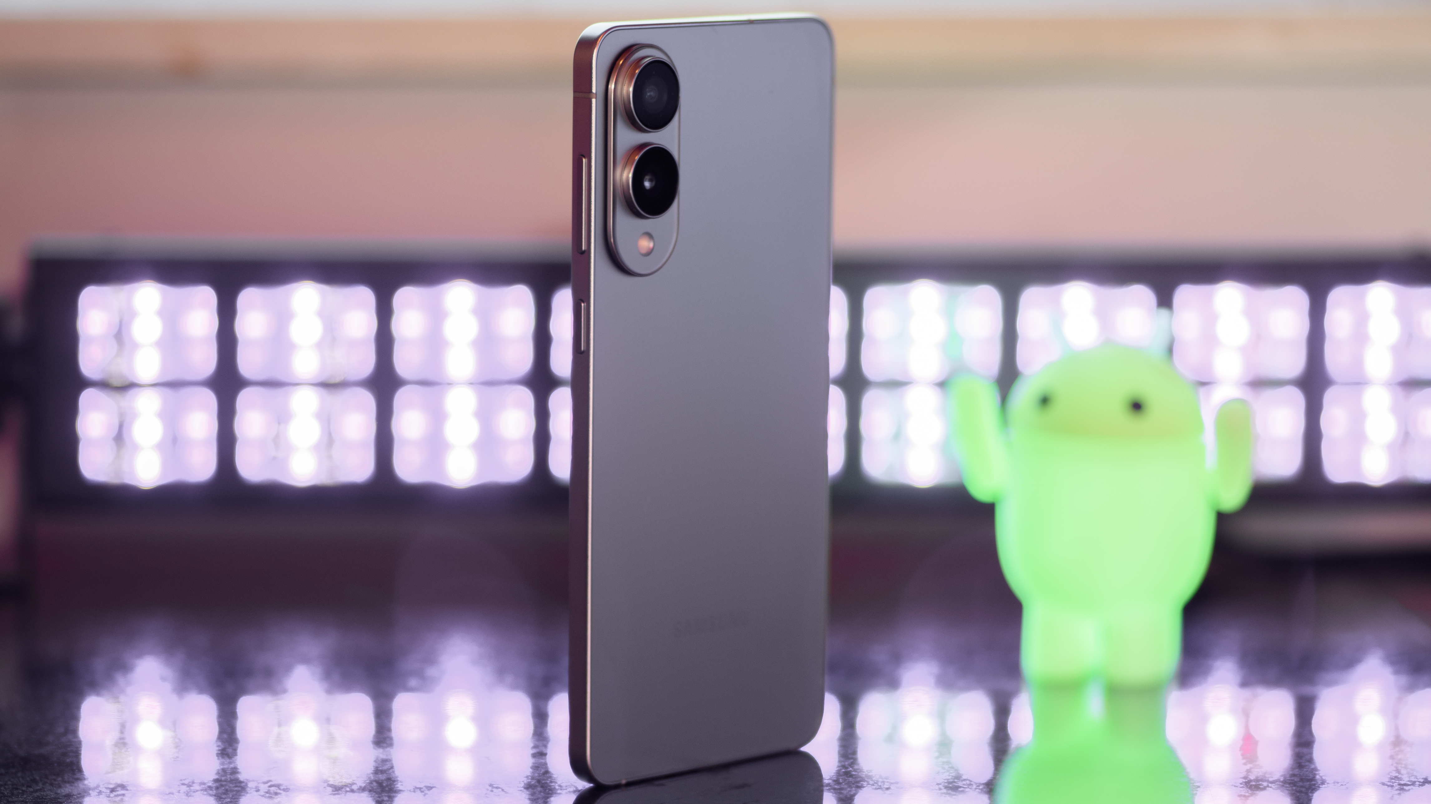 Samsung Galaxy S25 Edge from a 3/4 angle with black lights and an Android figurine blurred in the background