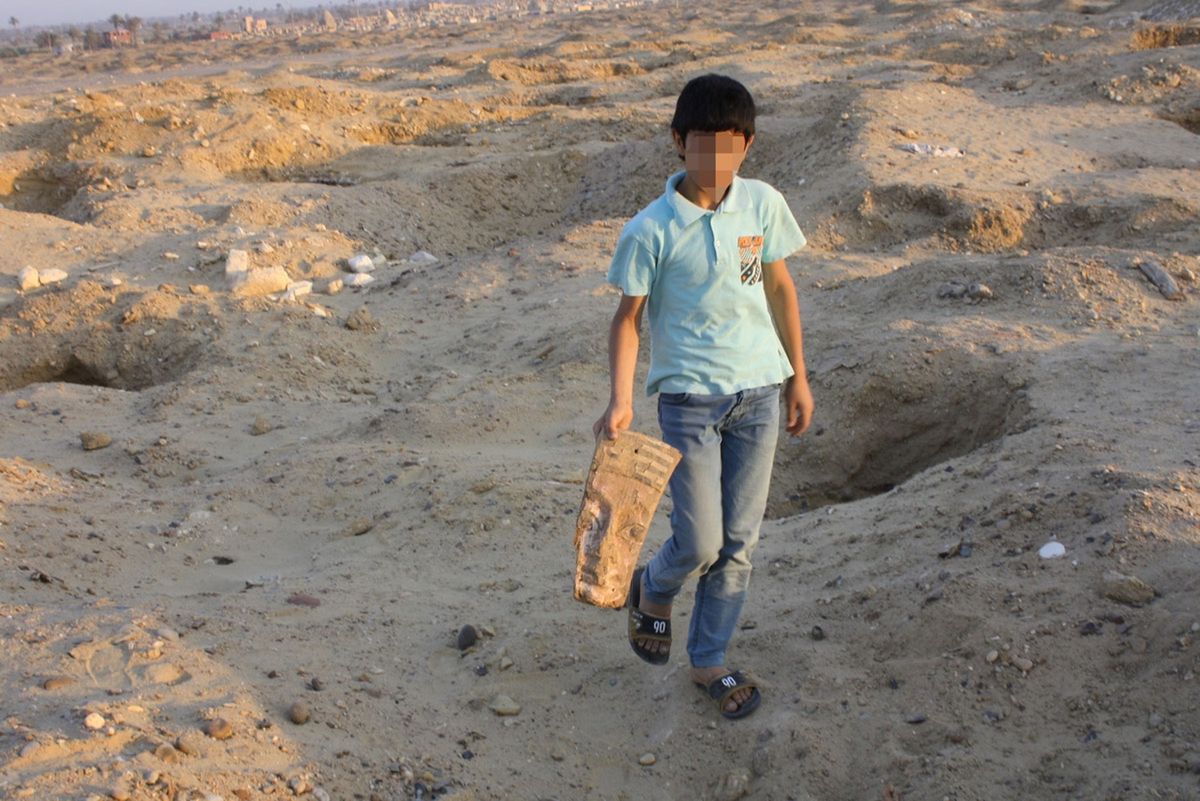 A child walks between looting pits dug at the ancient Egyptian site of Abusir el-Malek.