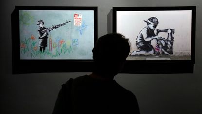 Visitor looks at Banksy artwork in exhibition in Rome in 2021