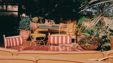 terrace restaurant with pot plants, steel frame furniture with terracotta and mustard upholstery and marble tables