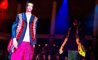 two male models on a fashion week runway in brightly coloured clothes