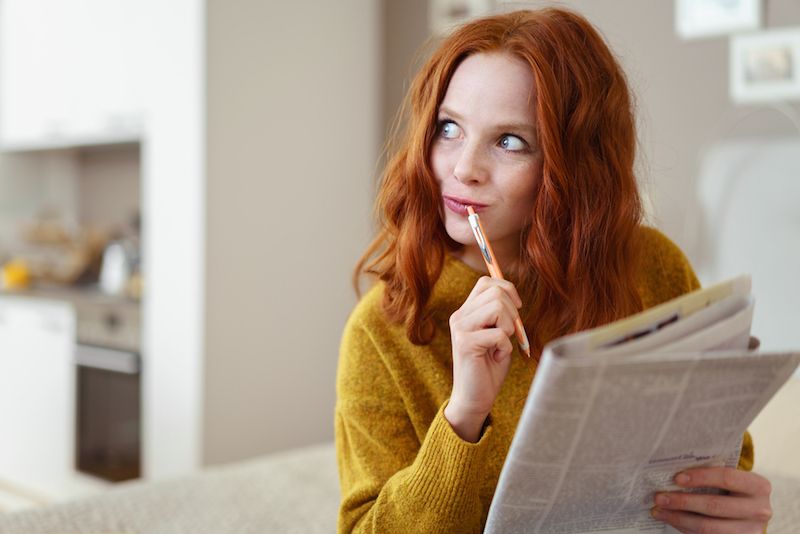 A woman sits solving a crossword puzzle.