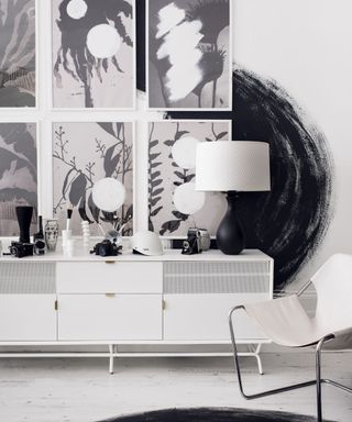 white and black designed wall frames on wall white sideboard and white chair