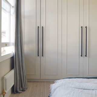 Fitted wardrobes in bedroom with black hardware.