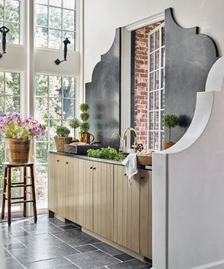 Detail of a kitchen with wooden farmhouse cabinetry and oversized slate splashback