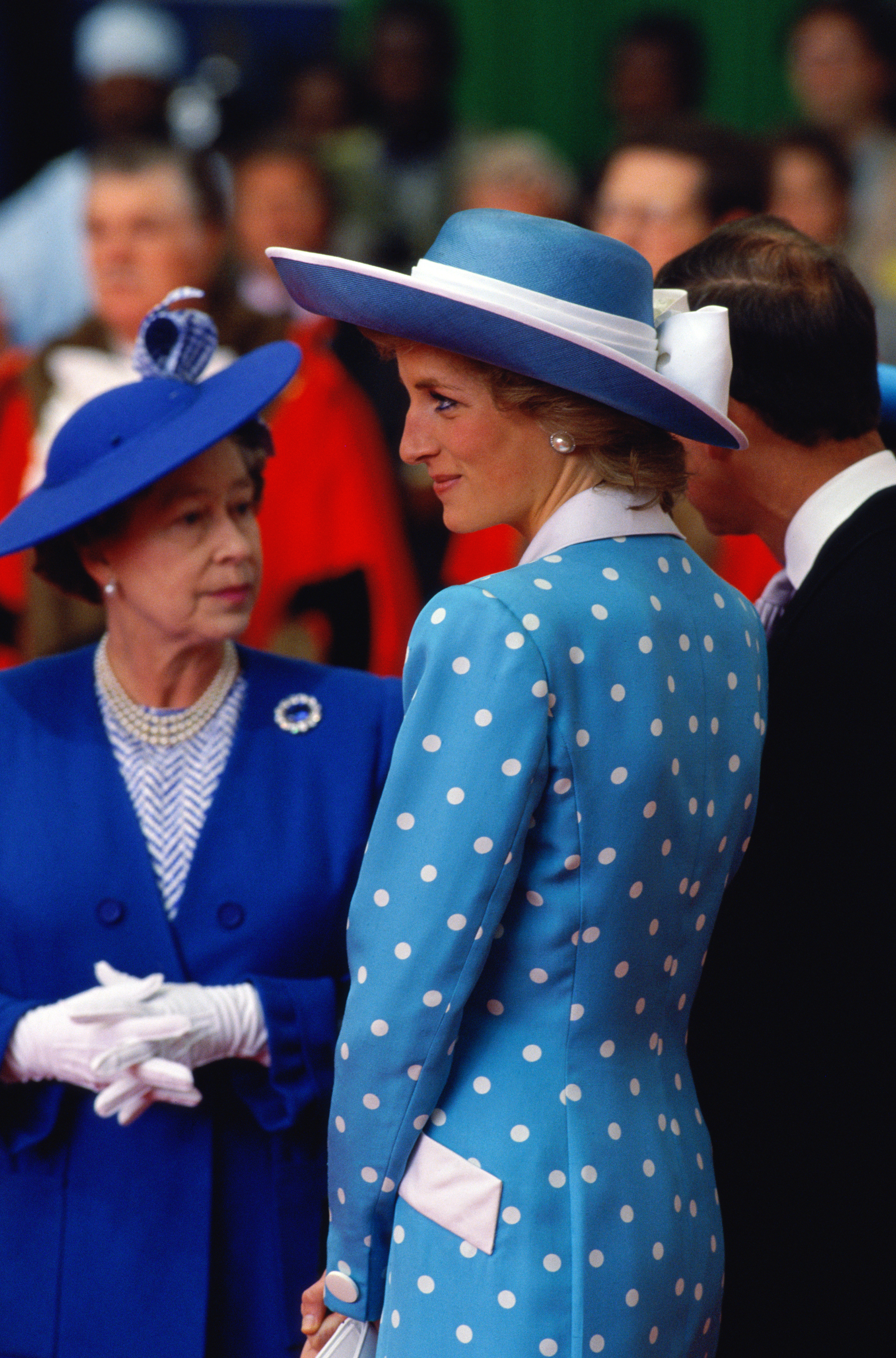 Queen Elizabeth wearing a blue coat next to Diana in a polka dot blue dress