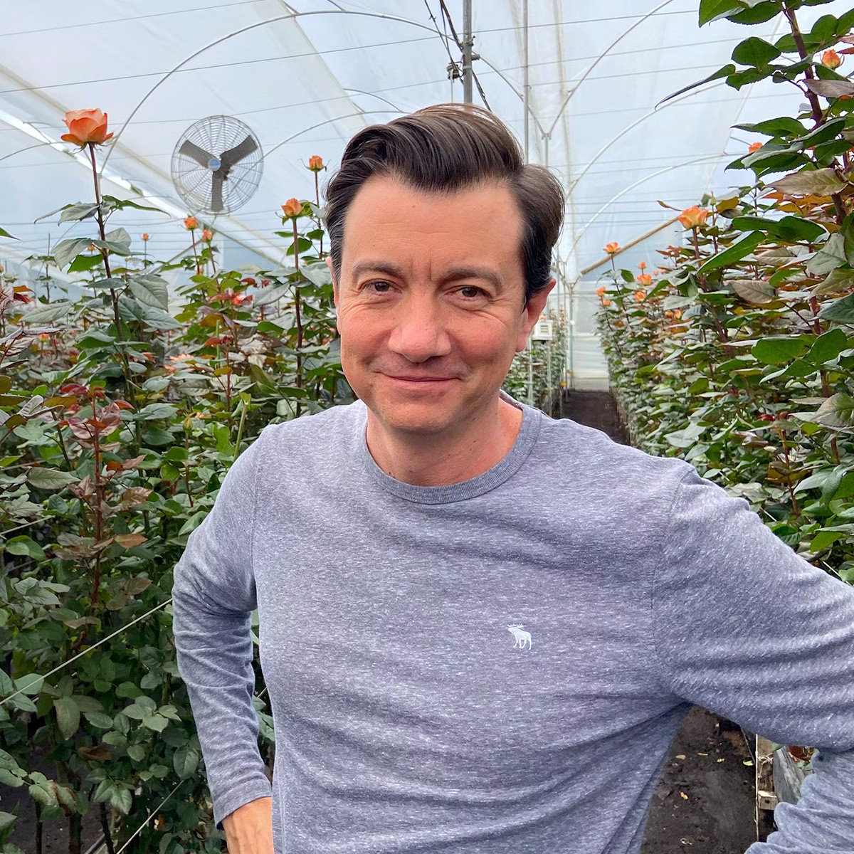 smiling headshot of Juan Palacio, CEO of BloomsyBox, with roses behind him