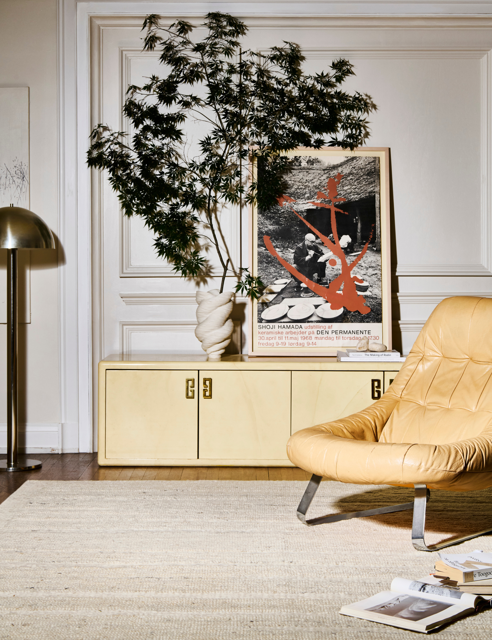 Cream colored handwoven rug anchoring a living room that features a chrome floor lamp, butter yellow sitting chair, and a similarly butter-toned credenza.