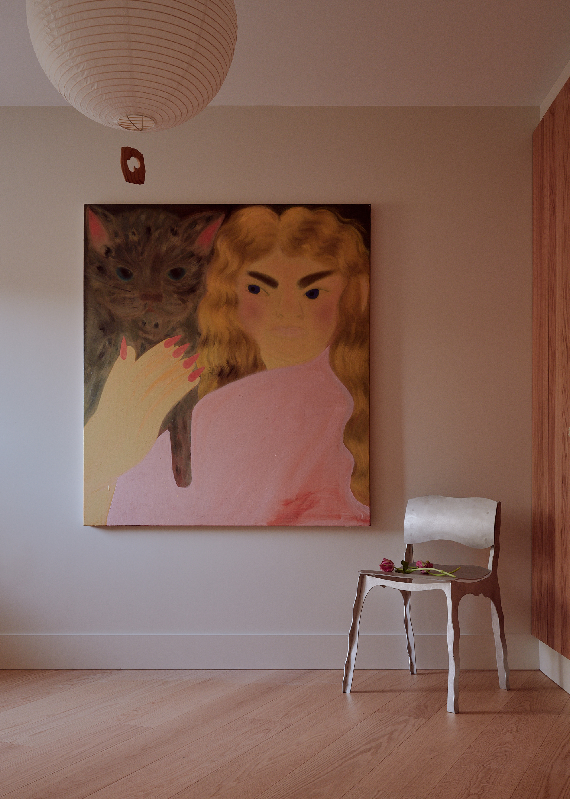 metal work chair and a big painting of a woman with a cat and a linen bulb