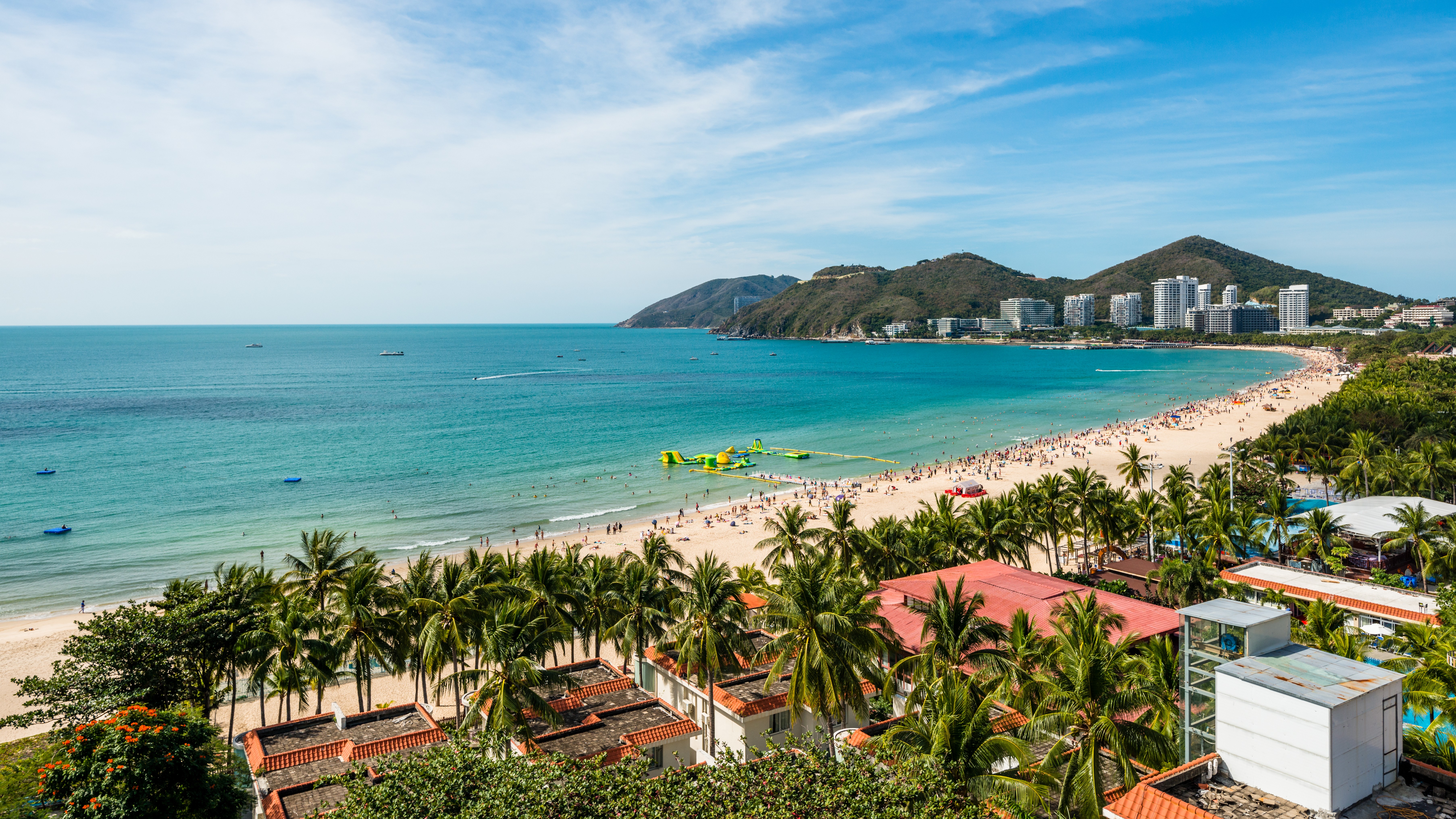 beach scene with palm trees and mountains in background in Hainan Island