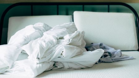 Bed linens crumpled on a white mattress