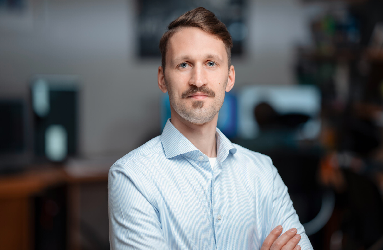 A man with a button up shirt has his arms crossed.