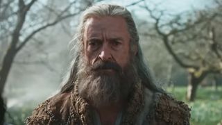 Hugh Jackman with a big grey beard, staring into the middle distance in The Death of Robin Hood