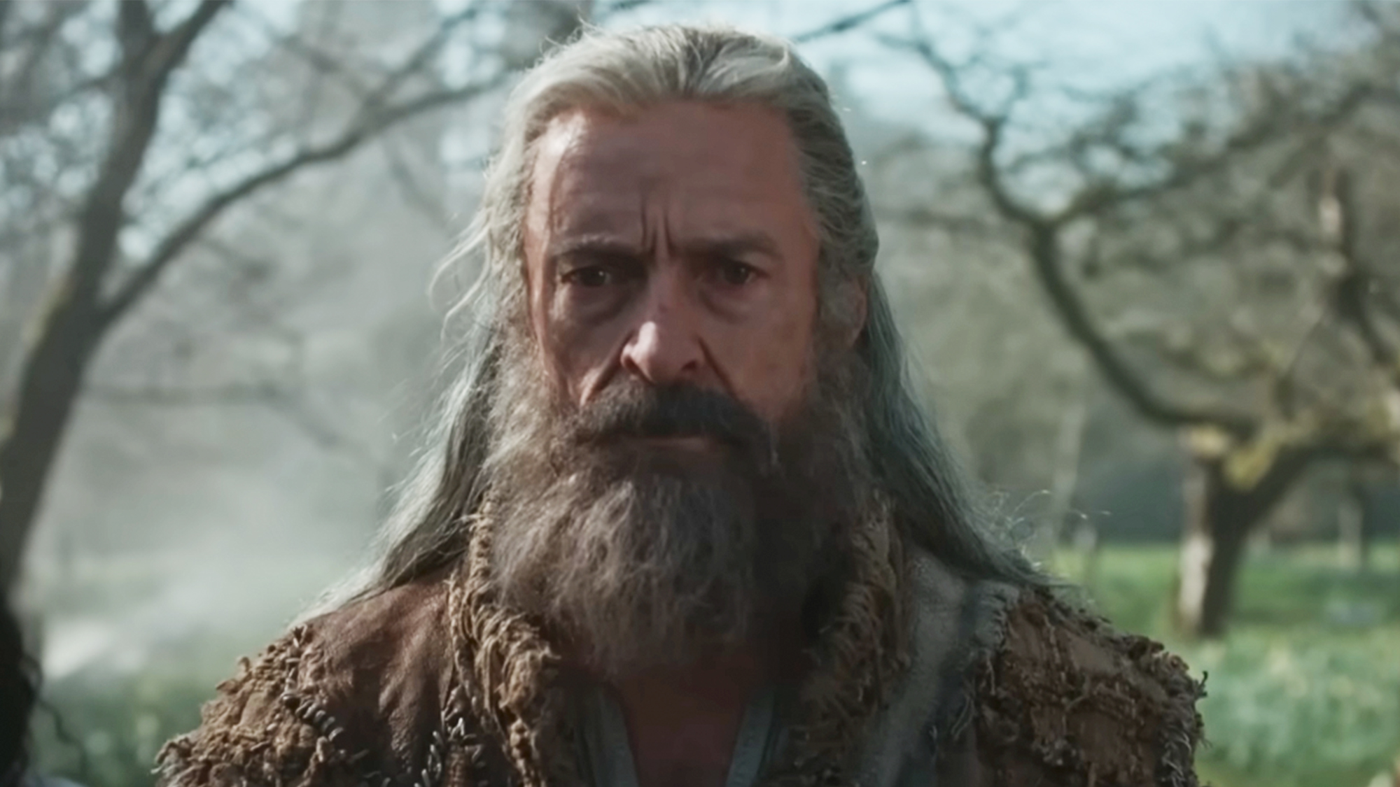 Hugh Jackman with a big grey beard, staring into the middle distance in The Death of Robin Hood