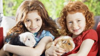 Two girls holding guinea pigs