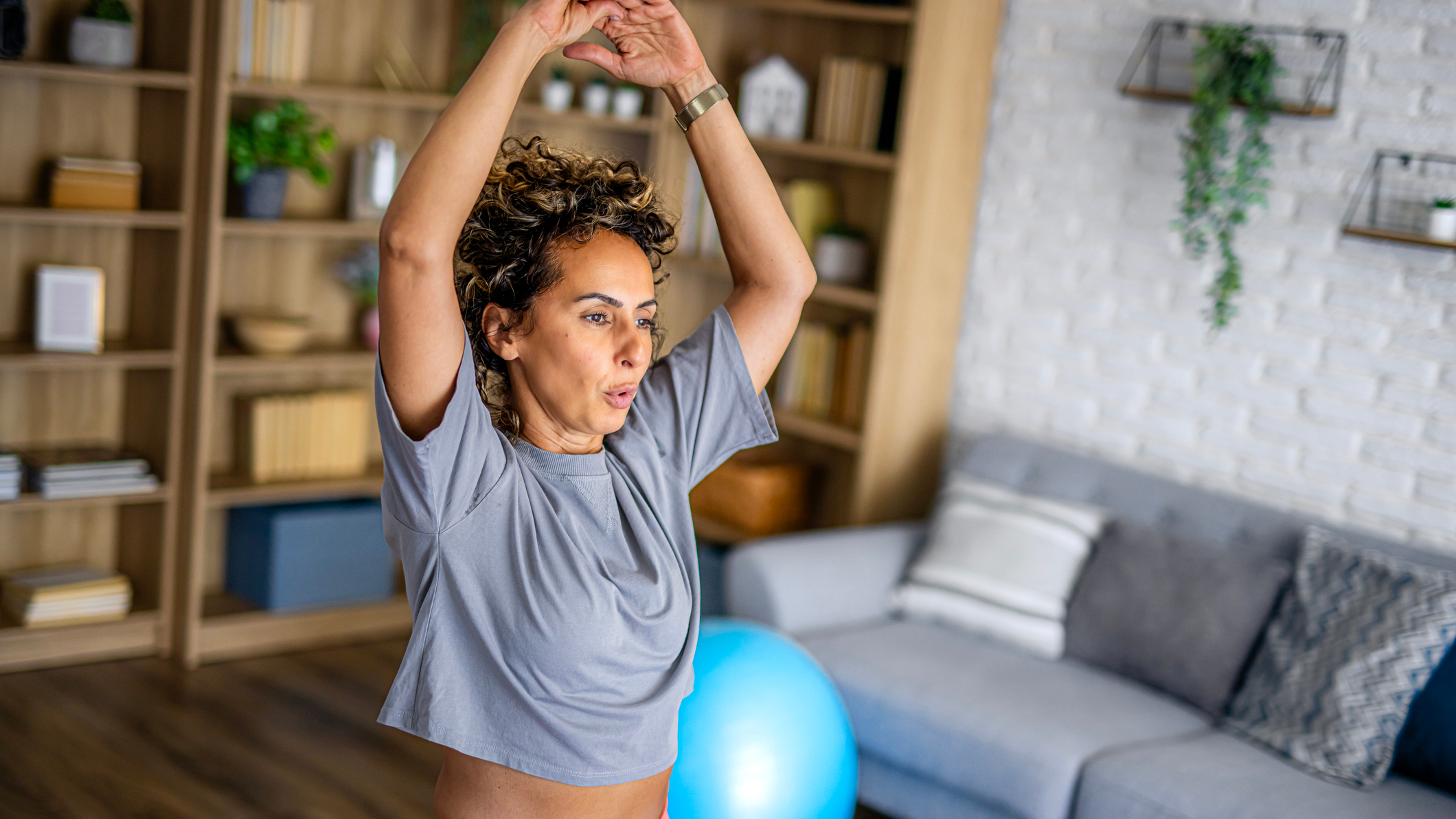 Woman exercising at home, with her arms raised above her head