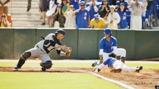 A baseball catcher dives to tag a player trying to score.