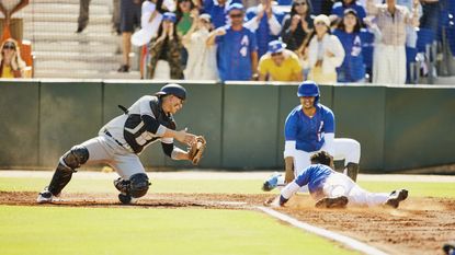 A baseball catcher dives to tag a player trying to score.