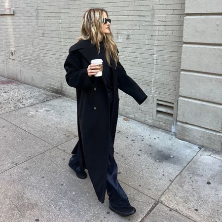 Eliza Huber wearing fall and winter basics, including a black long tailored coat, trousers, and a V-neck sweater. 