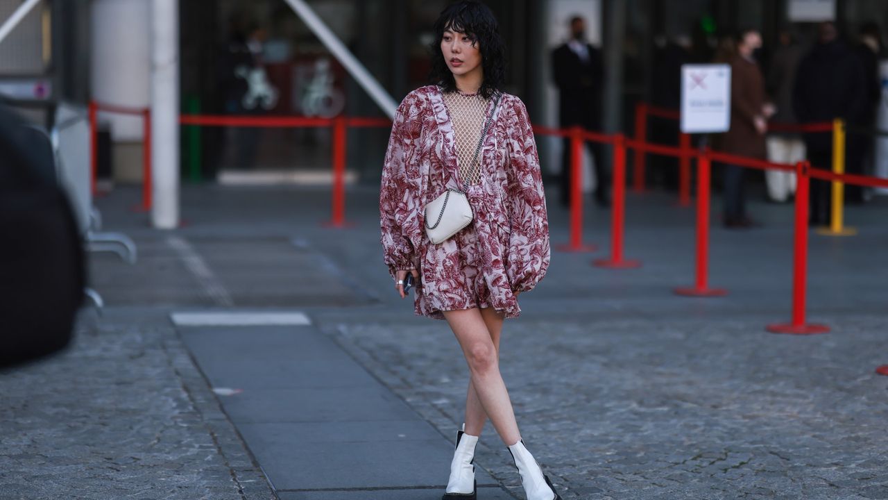  Xiayan Guo wearing a red short dress with floral design and white mesh and white leather Chelsea boots outside Stella McCartney during Paris Fashion Week on March 07, 2022 in Paris, France.